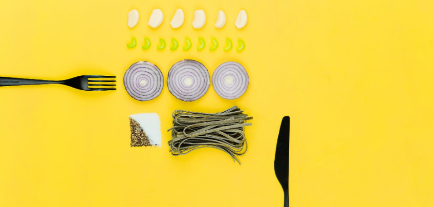 knife, fork and different food ingredients on a yellow surface
