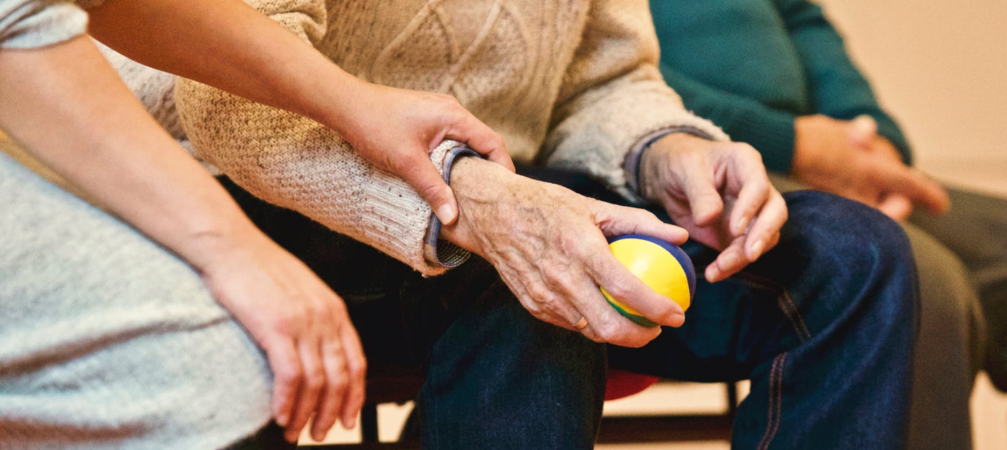 Young person holding an old person's hand with a small ball on hand